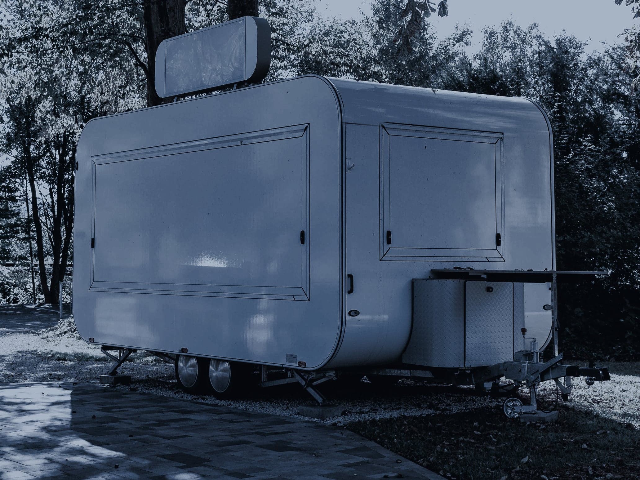 An enclosed box trailer with serving hatches, parked and hitched, ready to tow to an event.